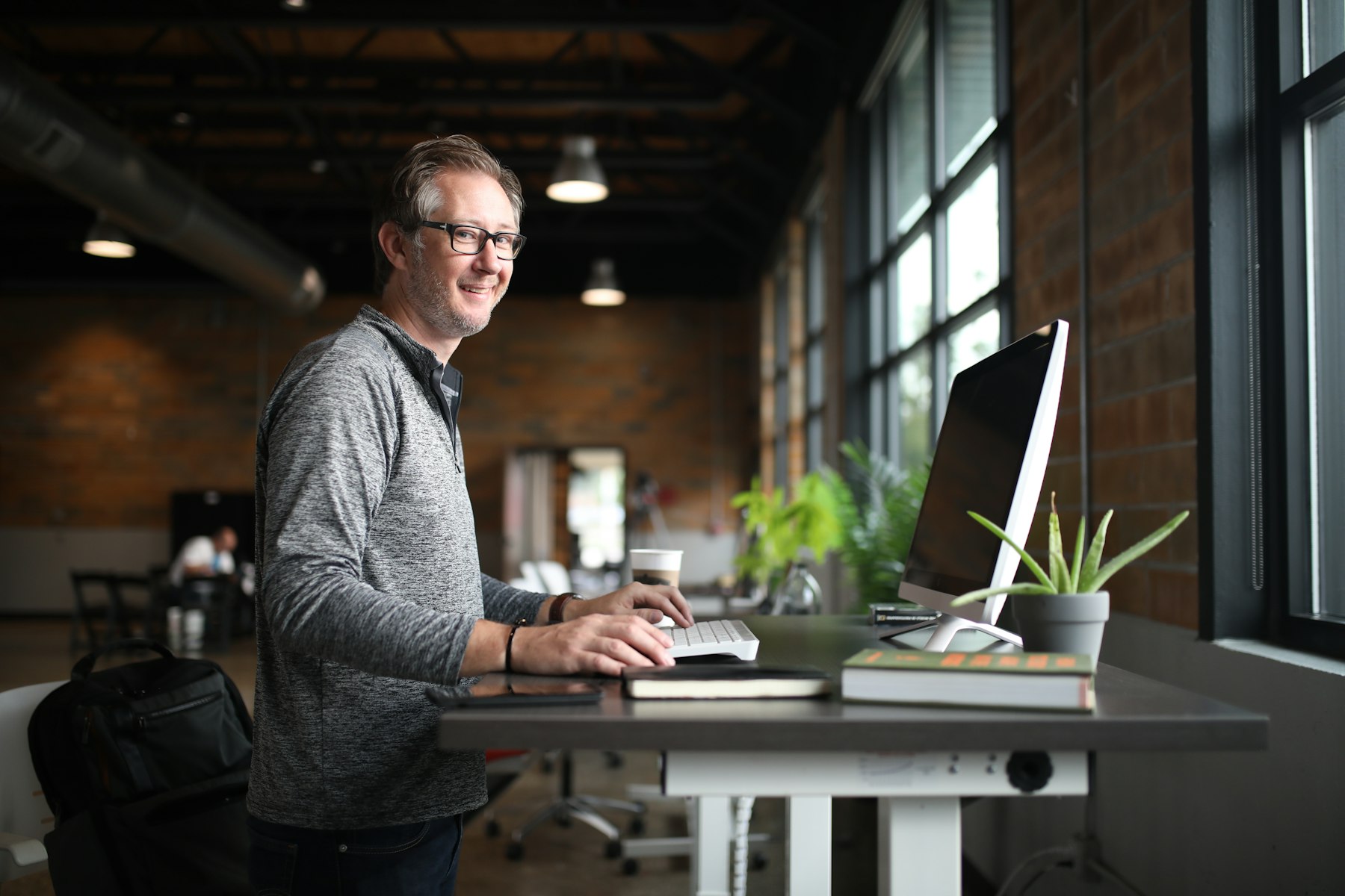 A person at a desk by a window, thinking
